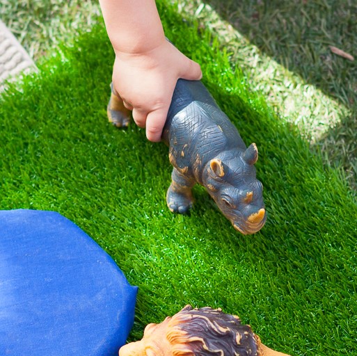 childs hand holding a toy rhino